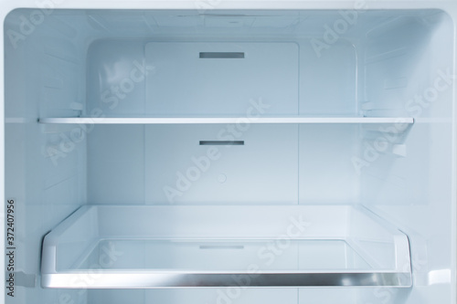 Clean empty shelves in white refrigerator. Empty open fridge with shelves, refrigerator. shelves in empty open white fridge background