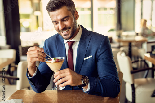 Happy businessman eating dessert while relaxing in a cafe.