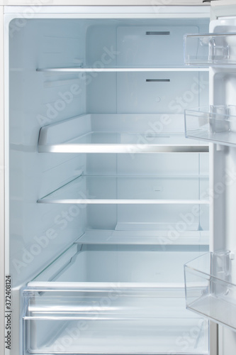 New white refrigerator. Empty shelves in fridge. background for health or diet concept.