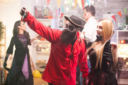 Attractive man and woman dressed up like pirate and vampire taking a selfie at halloween party.