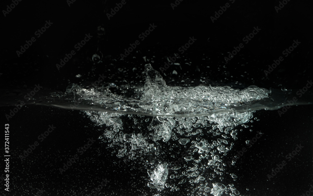 Obraz premium Water splashing as it's poured into aquarium tank, black background