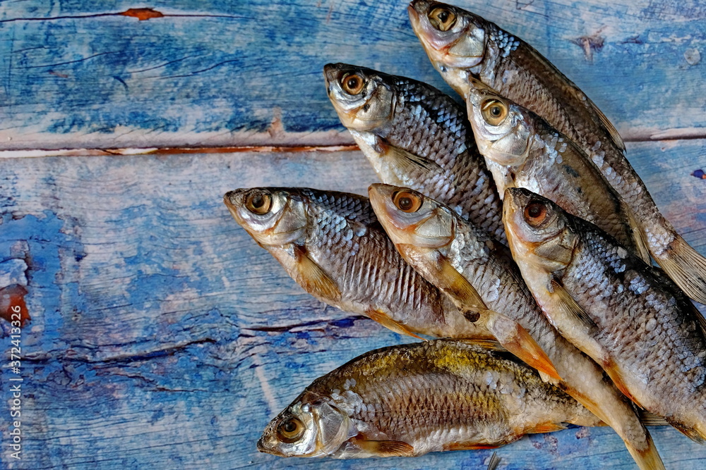  Salty dry river fish on a dark wooden background. Top view. Snack for beer. Copy space.