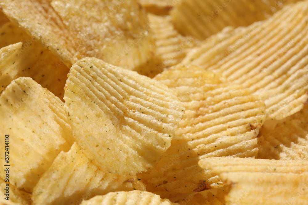 Background corrugated golden chips with texture. Potato chips is snack, ready to eat and fat food or junk food. Horizontal. Top view. Background corrugated golden chips with texture. Potato chips is snack, ready to eat and fat food or junk food. Horizontal. Top view.