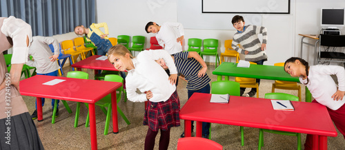 Fotografia Portrait of children stretching with friendly female teacher during physical act