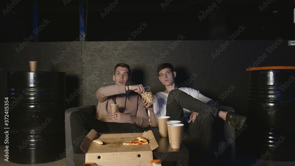 Naklejka premium In the Living Room two best Friends on Watching TV, And eatung popcorn