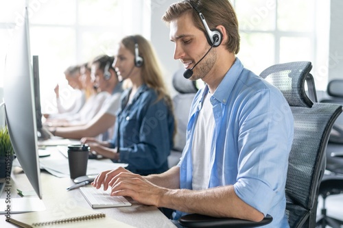 Schilderij op canvas Young handsome male customer support phone operator with headset working in call center