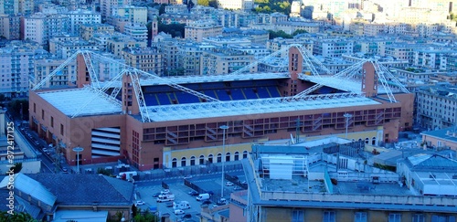 Genoa, Italy – August 5, 2020: Aerial view of shipping and container terminal, in the port of Genoa, and panoramic view to the other side of the city without the seaside, Stadium and residences.