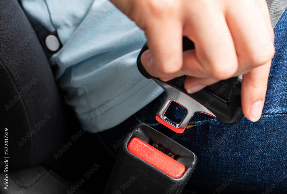 Close-up of a caucasian female hand holding a seat belt buckle for fastening in a car. Car safety concept