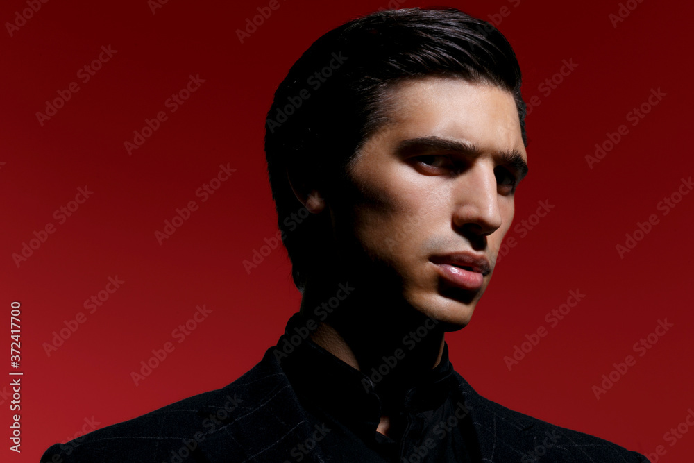 Close Up portrait of a handsome serious brutal man in black suit over red dark background. Horizontal view. Close Up portrait of a handsome serious brutal man in black suit over red dark background. Horizontal view.