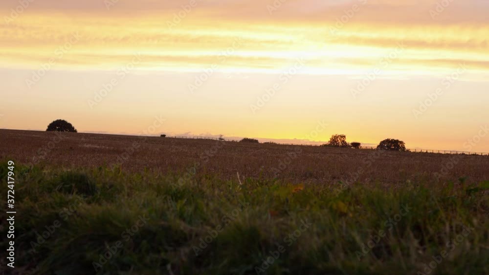 Sunset over farmers field with fencing silhouette in the distance Sunset over farmers field with fencing silhouette in the distance
