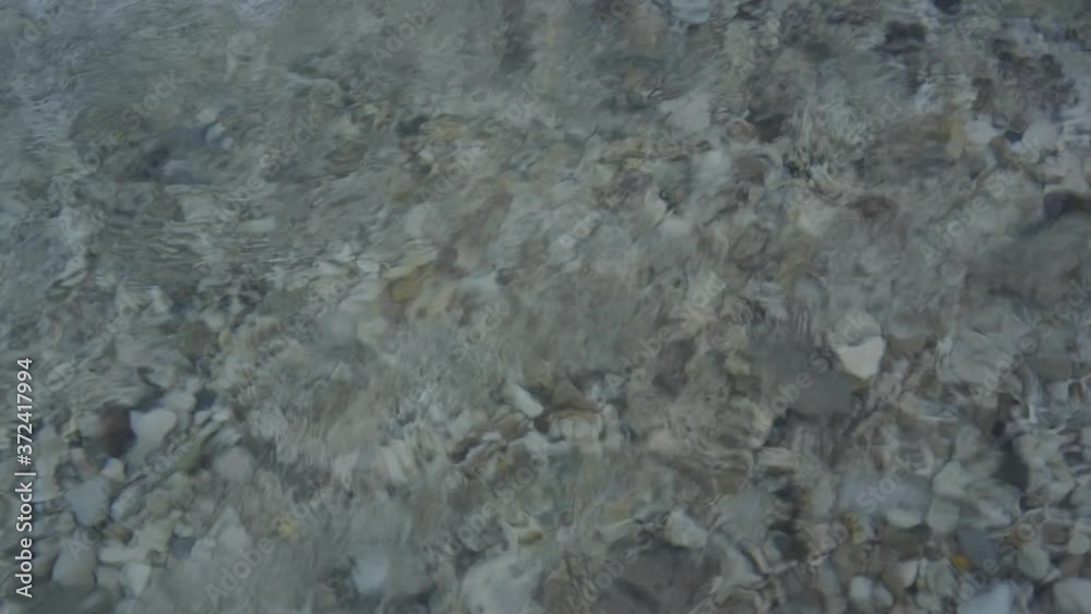 Pebbles of seabed on shore washed by clear crystal water of sea waves, close up pattern Pebbles of seabed on shore washed by clear crystal water of sea waves, close up pattern