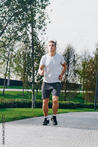 sports man in sneakers shorts and a t-shirt running in the park outdoors fitness