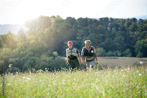 A father and son returning from a fly fishing trip and walking in a meadow