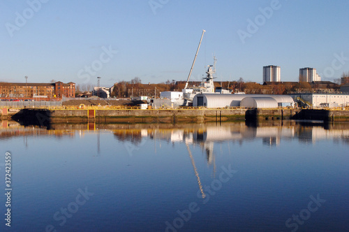 Industrial Area with Ship & Crane Reflected in Blue River Waters against Blue Sky 
