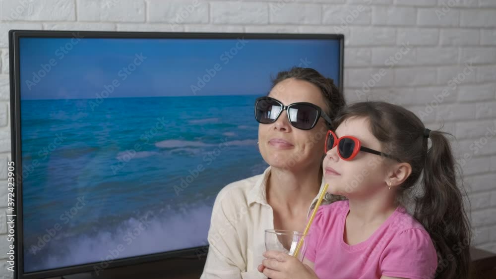 Upcoming vacation from home. A mother and daughter dream of rest, sitting in front of the TV screen. Upcoming vacation from home. A mother and daughter dream of rest, sitting in front of the TV screen.