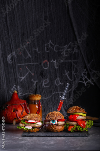 Homemade burger monsters for Halloween celebration on dark background. Halloween food and decoration.