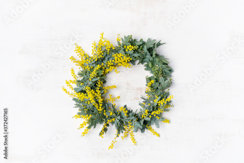 Beautiful Australian native yellow wattle/acacia flower wreath, photographed from above, on a white rustic background. Know as Acacia baileyana or Cootamundra wattle. photo