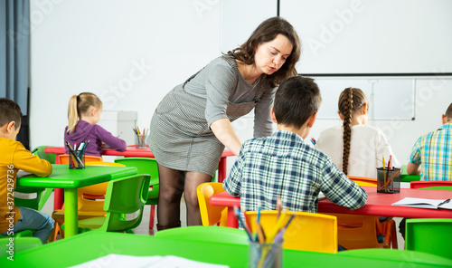 Young female teacher working with pupils in classroom at elementary school