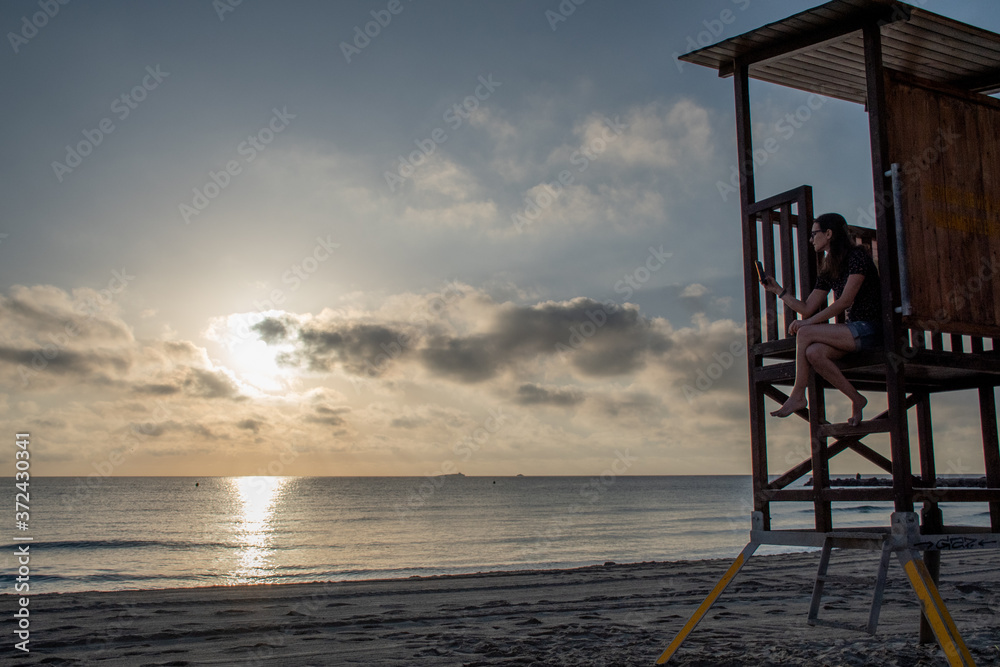 A woman reading in the beach during sunrise