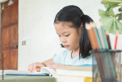 pretty stylish schoolgirl studying homework during online lesson at home  social distance during quarantine  self-isolation  online education concept  home school. girl does homework in her copybook