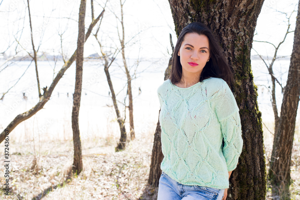 Woman in a knitted pullover walking in the park and posing
