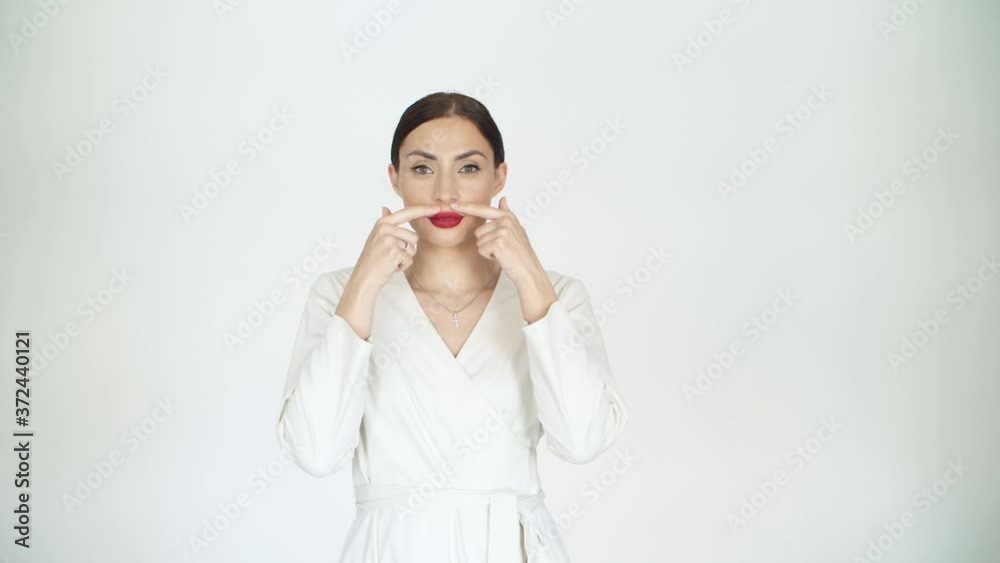 girl in a white jacket on a white background in the studio in slow motion shows the shape of her red lips girl in a white jacket on a white background in the studio in slow motion shows the shape of her red lips