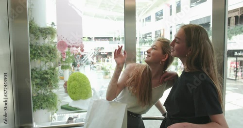 Portrait of two young beautiful women who lead an intresting conversation when they ridein the elevator. Laughing girls. 4K video photo