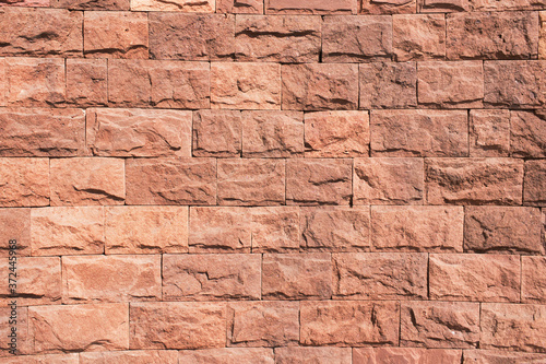 Red brick wall. Horizontal decorative uneven blocks background. Urban architecture texture. Solid stone texture. Grunge brickwork structure.