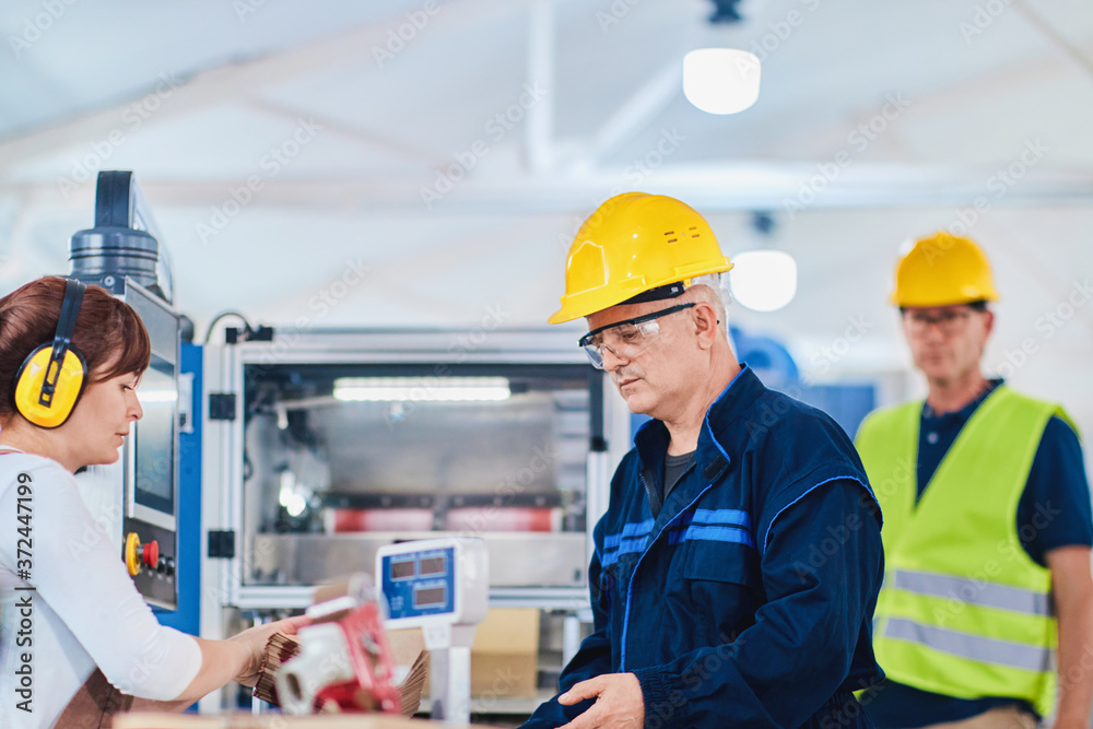 Man and woman workers in a factory, working as a team Man and woman workers in a factory, working as a team