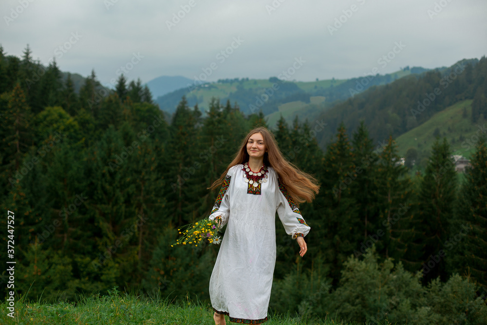 girl with flowing hair with a bouquet of wildflowers runs on green grass in the carpathians girl with flowing hair with a bouquet of wildflowers runs on green grass in the carpathians