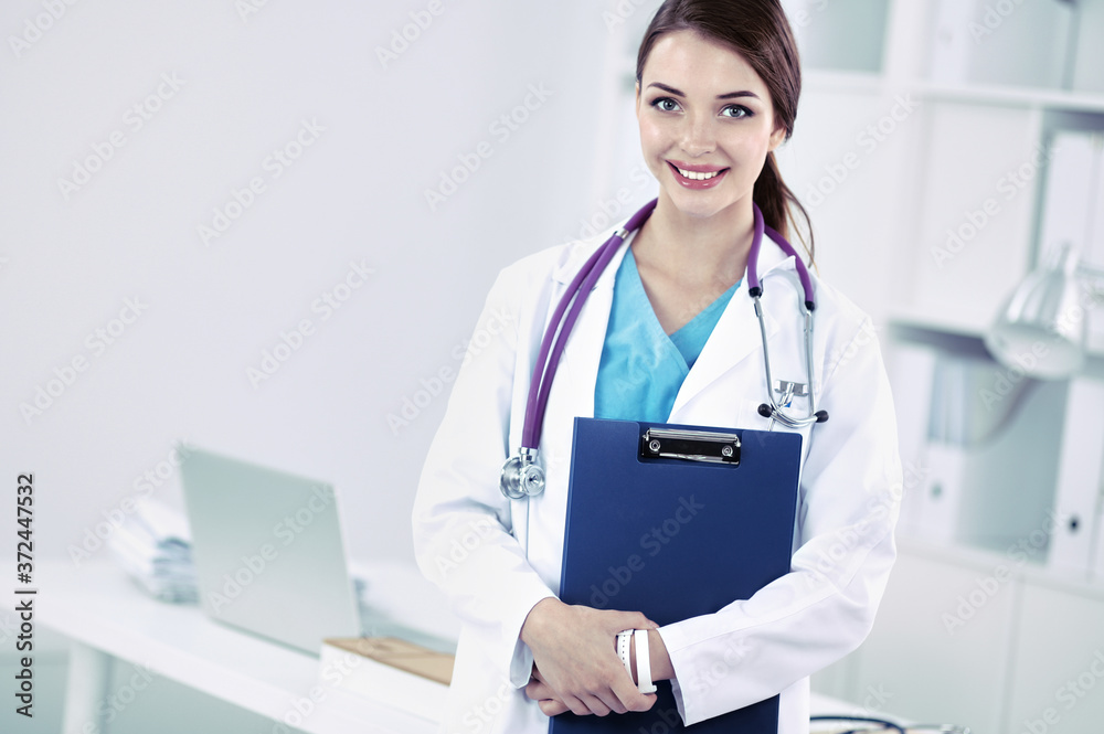 Smiling female doctor with a folder in uniform standing at hospital Smiling female doctor with a folder in uniform standing at hospital