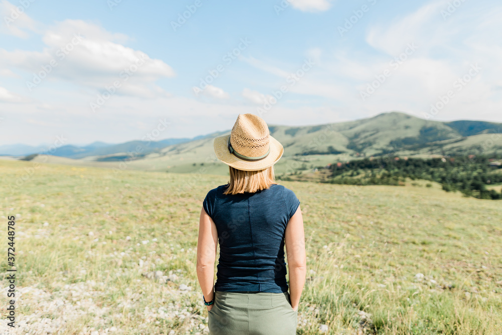 Young female nature lover enjoying the view of a mountain range in summertime