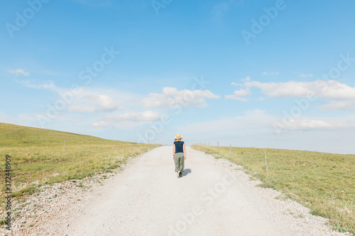 Young female nature explorer walking on a gravel road in summertime