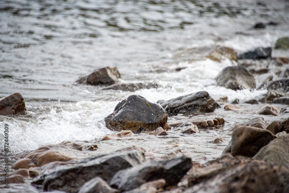 small stones on the seashore, the rolling waves of the sea with foam small stones on the seashore, the rolling waves of the sea with foam