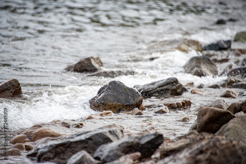 small stones on the seashore, the rolling waves of the sea with foam