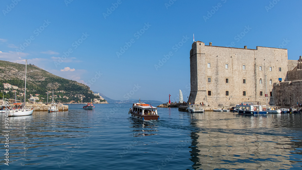 A boat leaving Dubrovnik harbour by the maritime museum in the old town, Croatia