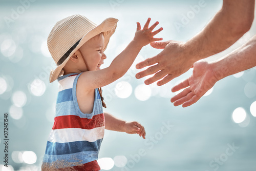 little boy playing with father at the beach in straw hat