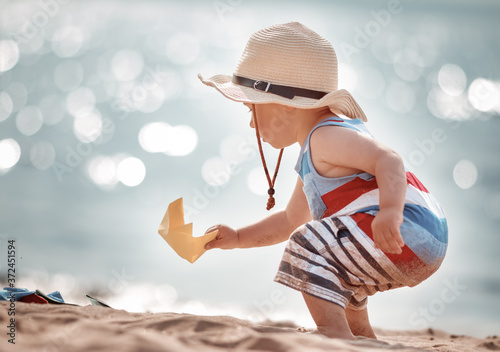 little boy playing at the beach in straw hat