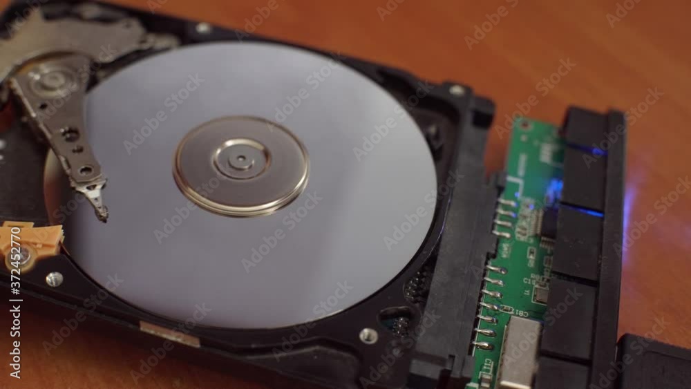 The hard disk is lying on the table, blinking and spinning the disk. Work of a hacked hard drive inside. Computer security. Internal structure of the hard disk. Lines of code and data flash in the bac The hard disk is lying on the table, blinking and spinning the disk. Work of a hacked hard drive inside. Computer security. Internal structure of the hard disk. Lines of code and data flash in the bac