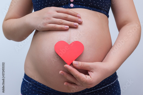 Wallpaper Mural A pregnant woman holds a heart symbol against the background of her stomach Torontodigital.ca