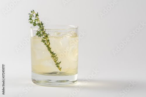 Alcoholic cocktail decorated with thyme in a glass glass on a white background