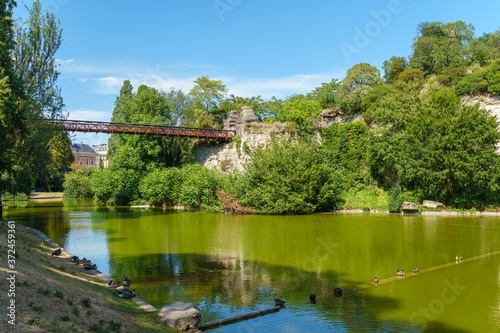 Lake in the Parc Buttes-Chaumont with footbridge in the background - Paris, France photo