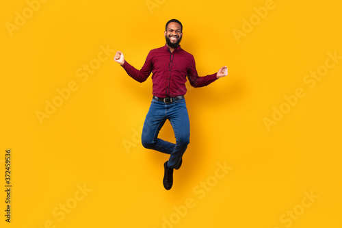 Happy black guy jumping and looking at camera