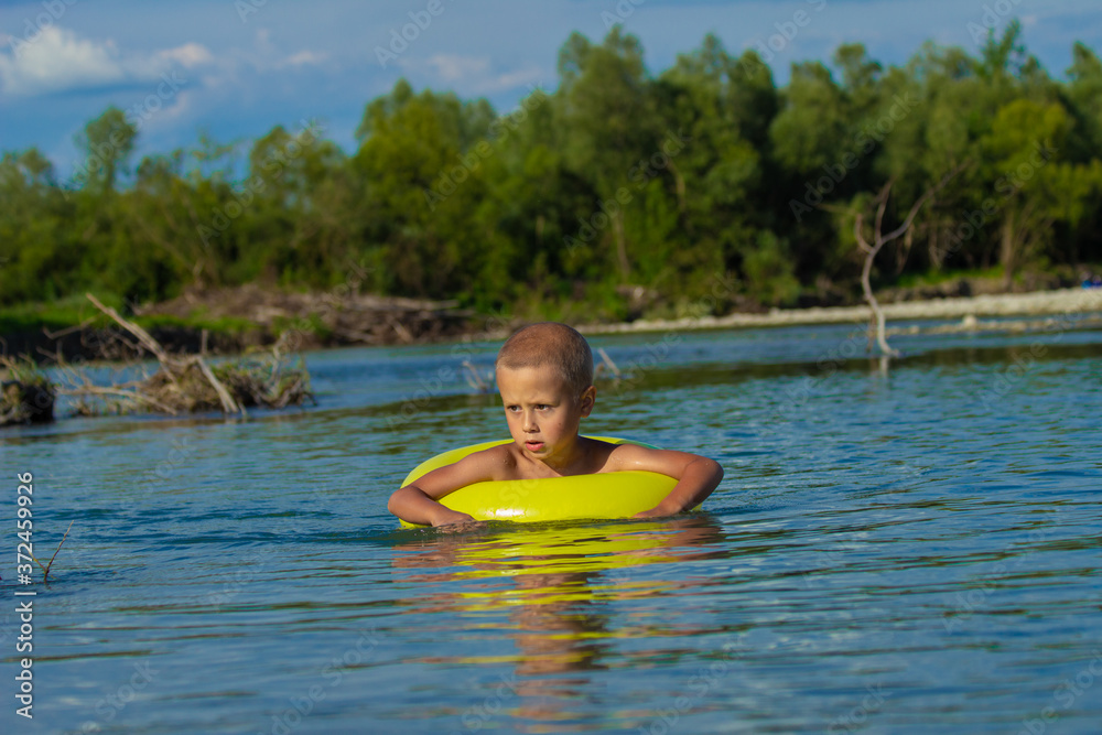 
a boy bathes in a river with an inflatable circle