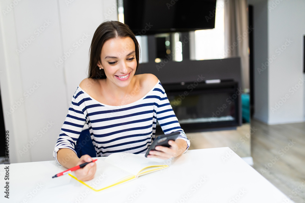 Young woman at home planning family budget and finances or calculated bills in the kitchen Young woman at home planning family budget and finances or calculated bills in the kitchen