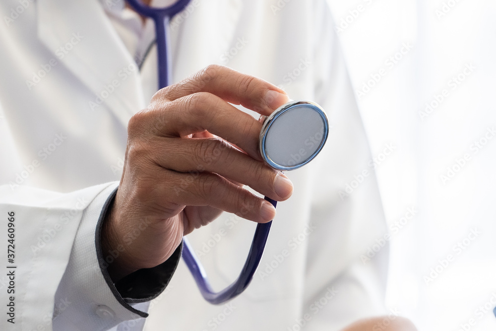 Midsection Of Doctor Holding Stethoscope At Clinic Midsection Of Doctor Holding Stethoscope At Clinic