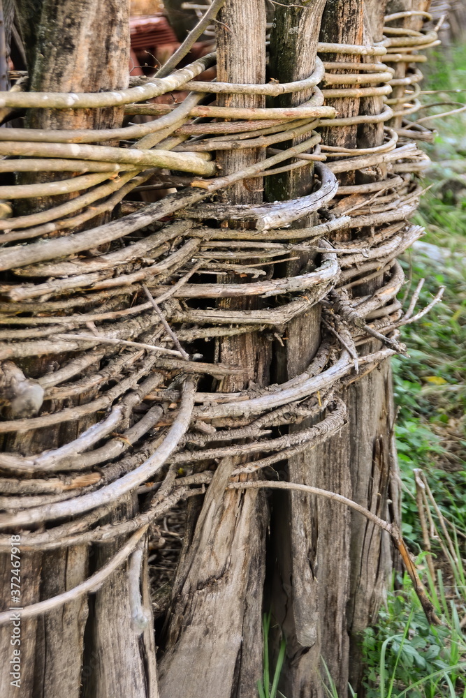 Wicker fence with wooden poles connected by twigs