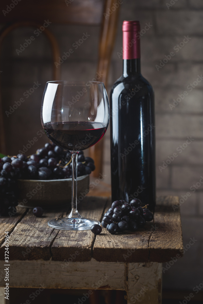 Red wine in a glass and ripe grapes on wooden table