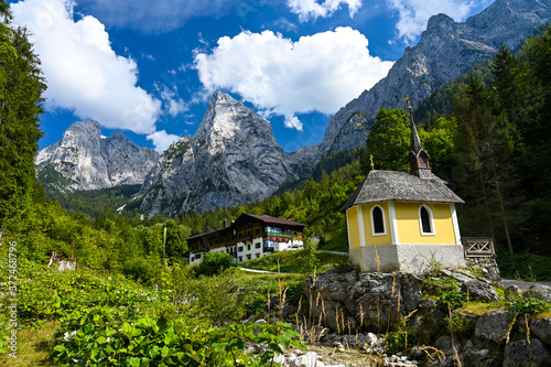 Fantastic view of a chapel and an alpine hut in the Kaiser valley surrounded by forest and the rough Kaiser Mountains.
