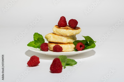 Delicious and healthy cottage cheese pancakes on a white saucer, poured with BlackBerry jam.